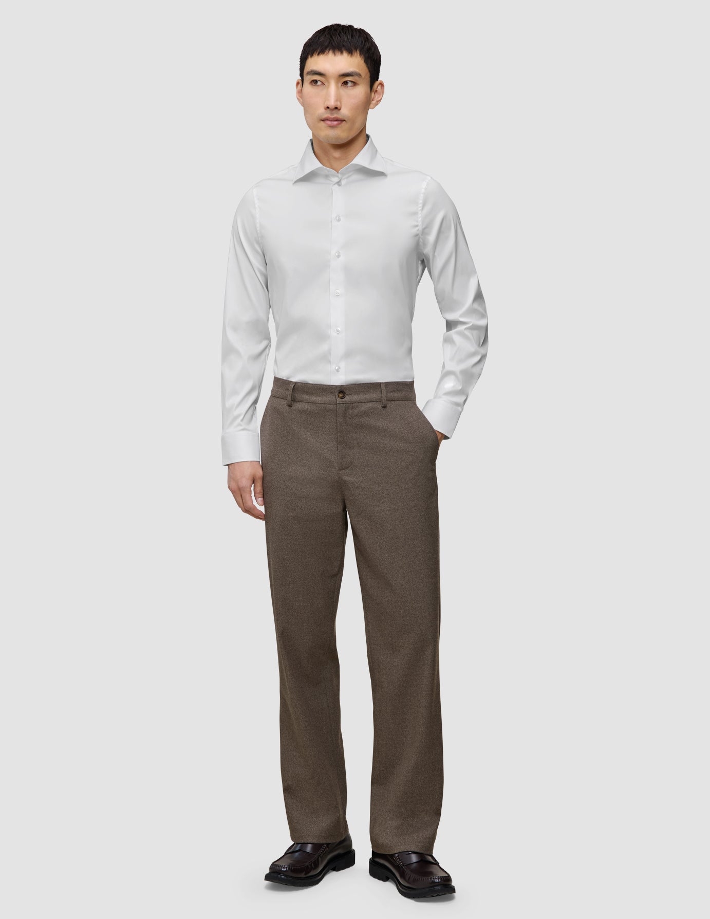 En mann kledd i en hvit, smal Elevated Shirt i Pima-bomull og brune bukser.